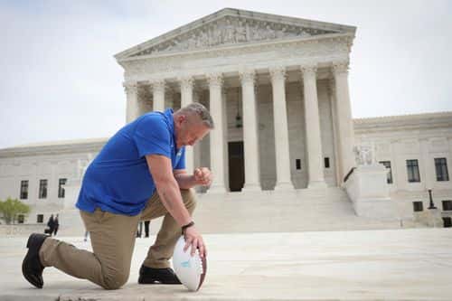Former Bremerton High School assistant football coach Joe Kennedy takes a knee in front of the U.S. Supreme Court after his legal case, Kennedy vs. Bremerton School District, was argued before the court on April 25, 2022 in Washington, DC. Kennedy was terminated from his job by Bremerton public school officials in 2015 after refusing to stop his on-field prayers after football games.