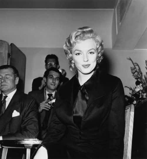 American actress Marilyn Monroe (1926 - 1962) at a press conference at the Savoy Hotel, London, July 1956. Monroe is in England to film 'The Prince and the Showgirl' with English actor and director Laurence Olivier (1907 - 1989, far left). (Photo by Harry Kerr/BIPs/Hulton Archive/Getty Images)
