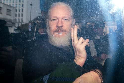 Julian Assange gestures to the media from a police vehicle on his arrival at Westminster Magistrates court on April 11, 2019 in London, England.  After weeks of speculation Wikileaks founder Julian Assange was arrested by Scotland Yard Police Officers inside the Ecuadorian Embassy in Central London this morning. Ecuador's President, Lenin Moreno, withdrew Assange's Asylum after seven years citing repeated violations to international conventions.