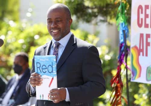 California State Superintendent of Schools Tony Thurmond holds the book 