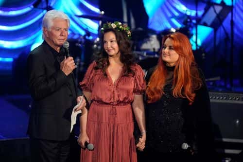(L-R) Larry Strickland, Ashley Judd, and Wynonna Judd speak onstage for Naomi Judd: 'A River Of Time' Celebration at Ryman Auditorium on May 15, 2022 in Nashville, Tennessee.