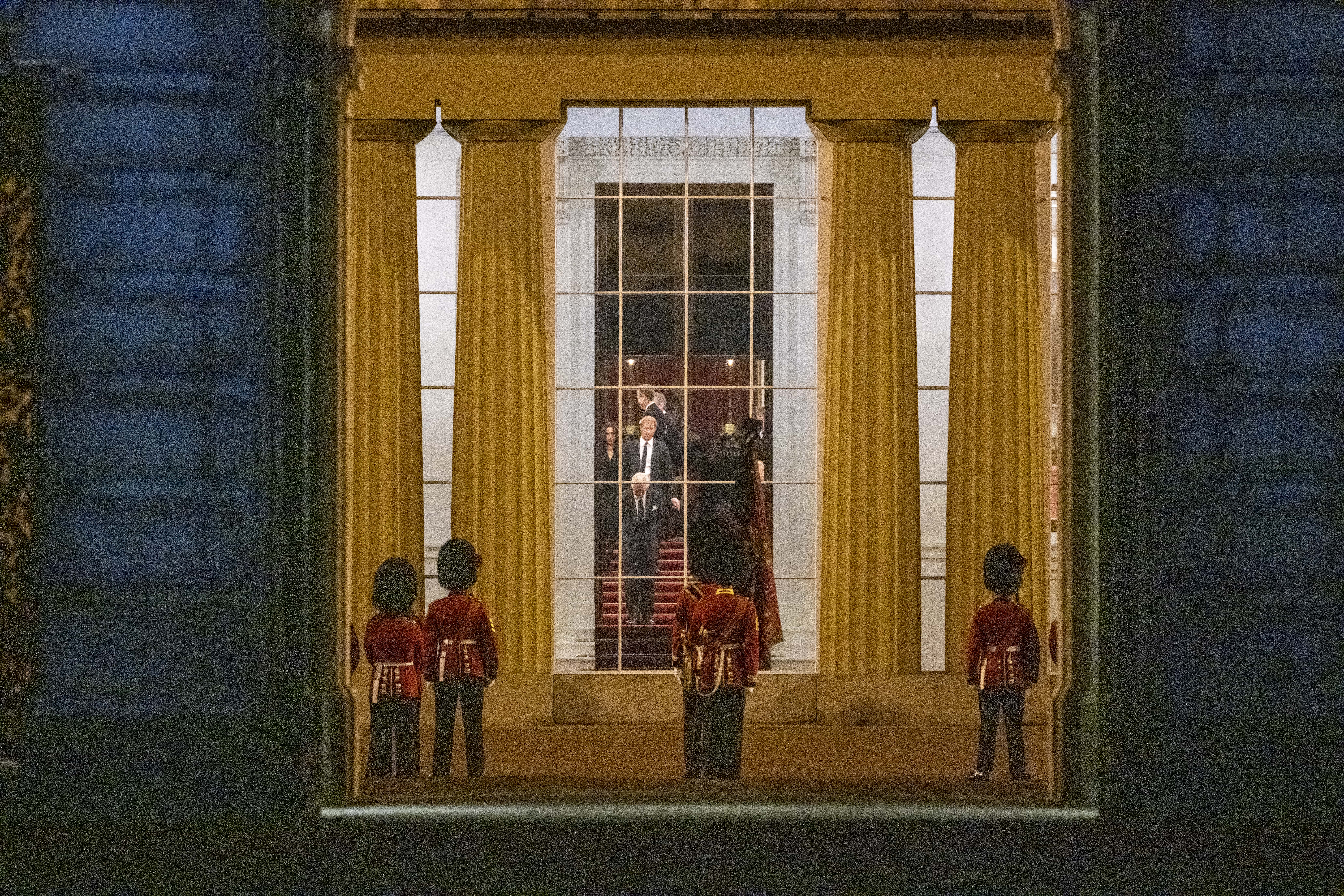 King Charles III, Prince Harry, Duke of Sussex, and Meghan, Duchess of Sussex wait for the the Royal Hearse carrying the coffin of Queen Elizabeth II to arrive at Buckingham Palace on September 13, 2022 in London, England. The coffin carrying Her Majesty Queen Elizabeth II leaves St Giles Church travelling to Edinburgh Airport where it will be flown to London and transferred to Buckingham Palace by road. Queen Elizabeth II died at Balmoral Castle in Scotland on September 8, 2022, and is succeeded by her eldest son, King Charles III.