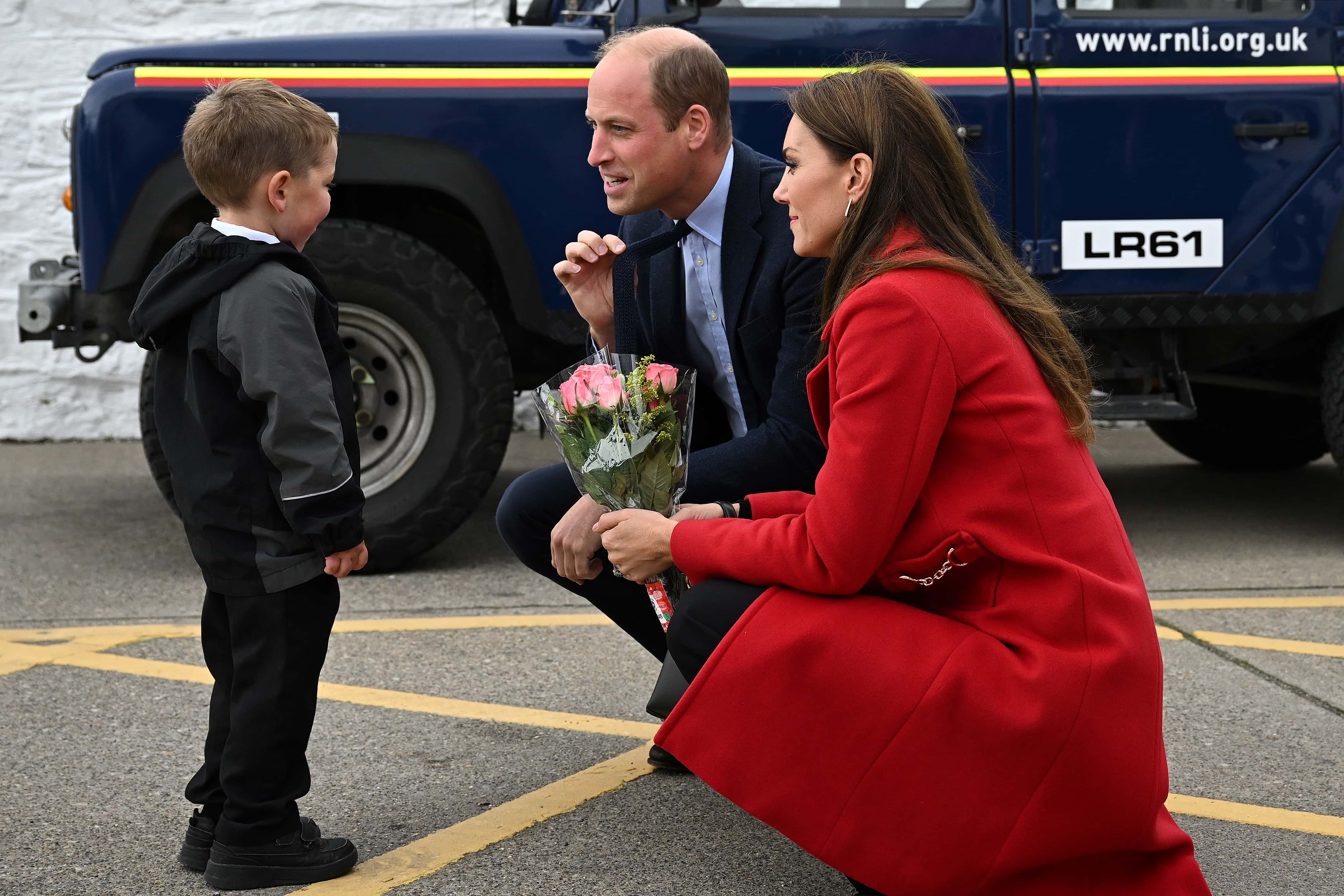 Prince William, Prince of Wales (C) gestures as his wife Catherine, Princess of Wales is presented with a posy of flowers by four-year-old Theo Crompton during their visit to the RNLI (Royal National Lifeboat Institution) Holyhead Lifeboat Station, during a visit to Wales on September 27, 2022 in Holyhead, Wales.
