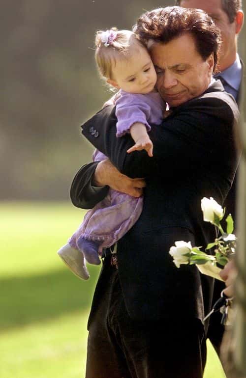 Actor Robert Blake hugs his 11-month-old daughter, Rose Lenore Sophie Blake, as she leans down to grab a white rose picked from the coffin bearing her slain mother, Bonny Lee Bakley, during a brief funeral ceremony May 25, 2001 in Los Angeles, CA.