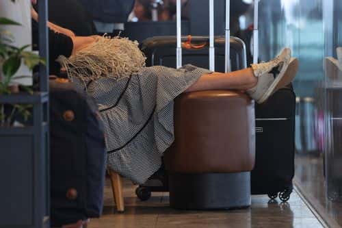 A passenger with suitcases relaxes in the main departures hall at Terminal 1 at Berlin Brandenburg Airport on the first day of the local summer school vacation on July 07, 2022 in Schoenefeld, Germany. Both airports and airlines in Germany have recently encountered difficulties due to to staff shortages resulting from Covid-era layoffs, though today's passenger processing at Berlin Brandenburg Airport appeared to be running smoothly.