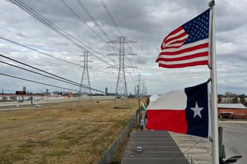 The U.S. and Texas flags fly in front of high voltage transmission towers on February 21, 2021 in Houston, Texas. Millions of Texans lost power when winter storm Uri hit the state and knocked out coal, natural gas and nuclear plants that were unprepared for the freezing temperatures brought on by the storm. Wind turbines that provide an estimated 24 percent of energy to the state became inoperable when they froze.