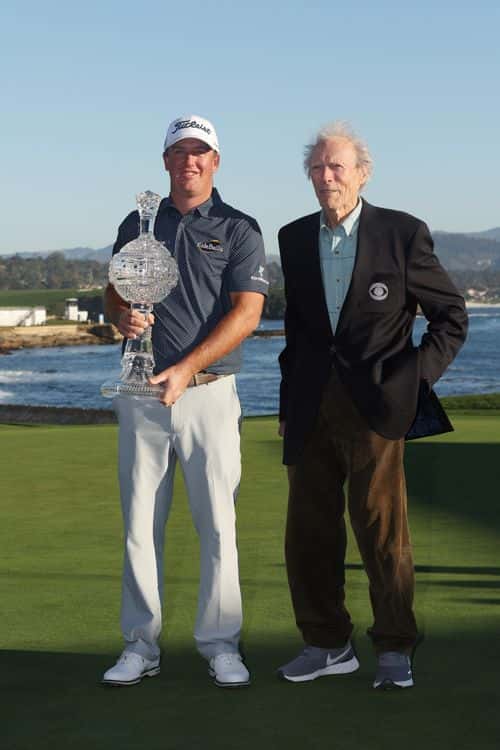 Tom Hoge of the United States celebrates with the trophy and actor Clint Eastwood after winning during the final round of the AT&T Pebble Beach Pro-Am at Pebble Beach Golf Links on February 06, 2022 in Pebble Beach, California.